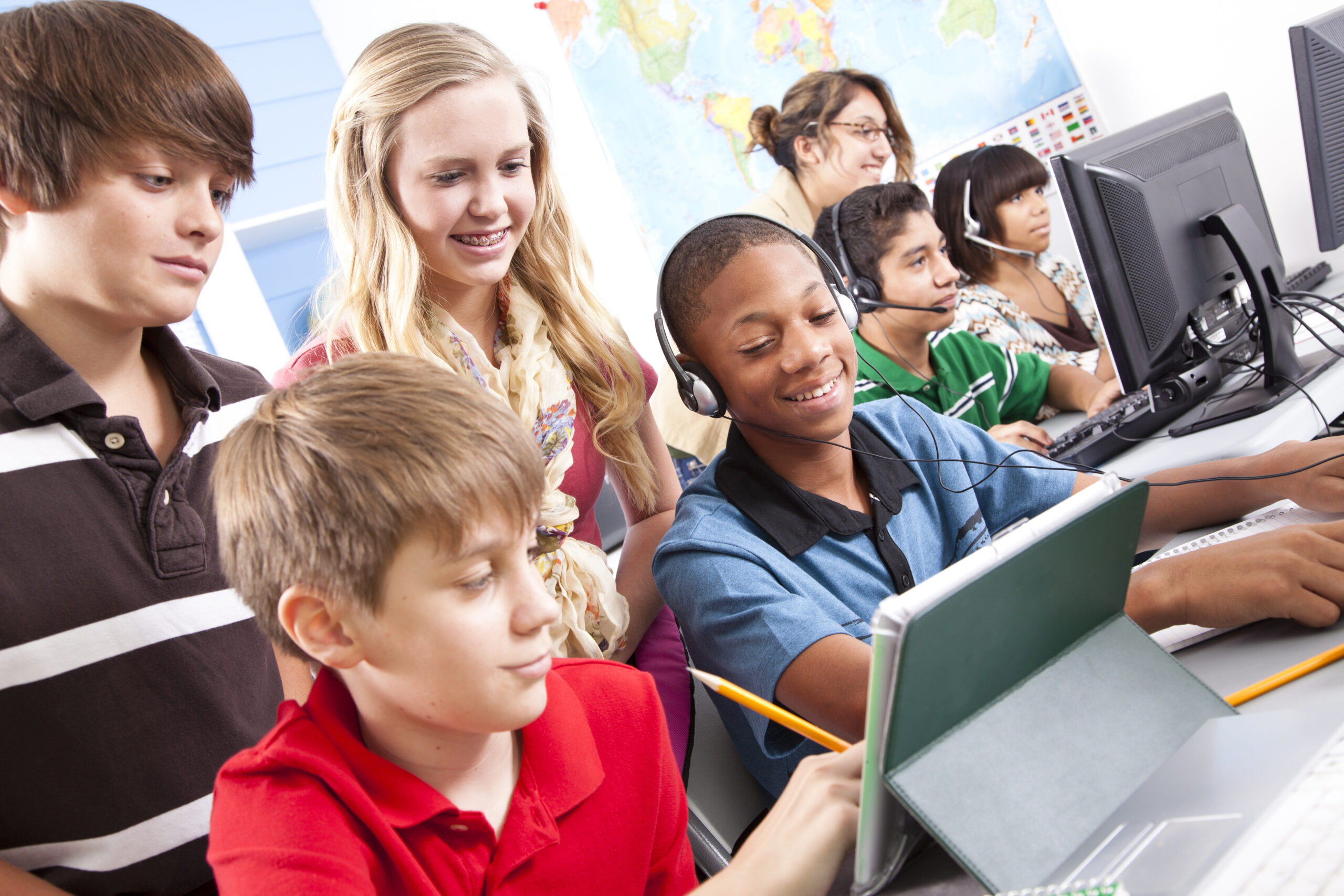 Pre-teen students in computer lab with instructor. Classroom, school, education.