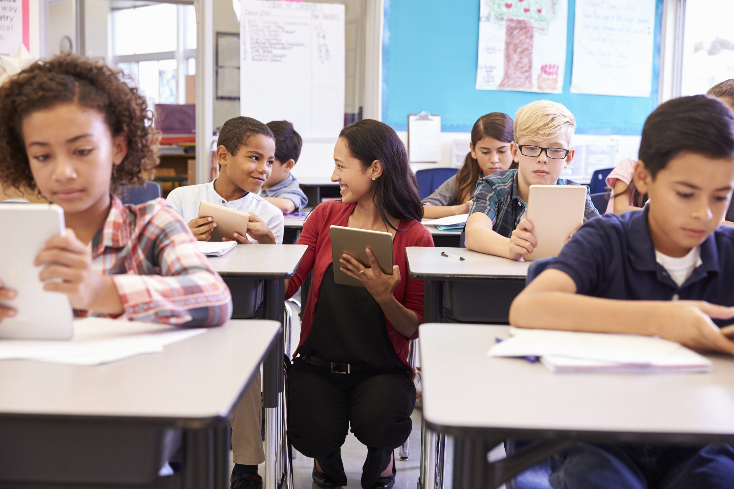 Teacher among kids with computers in elementary school class