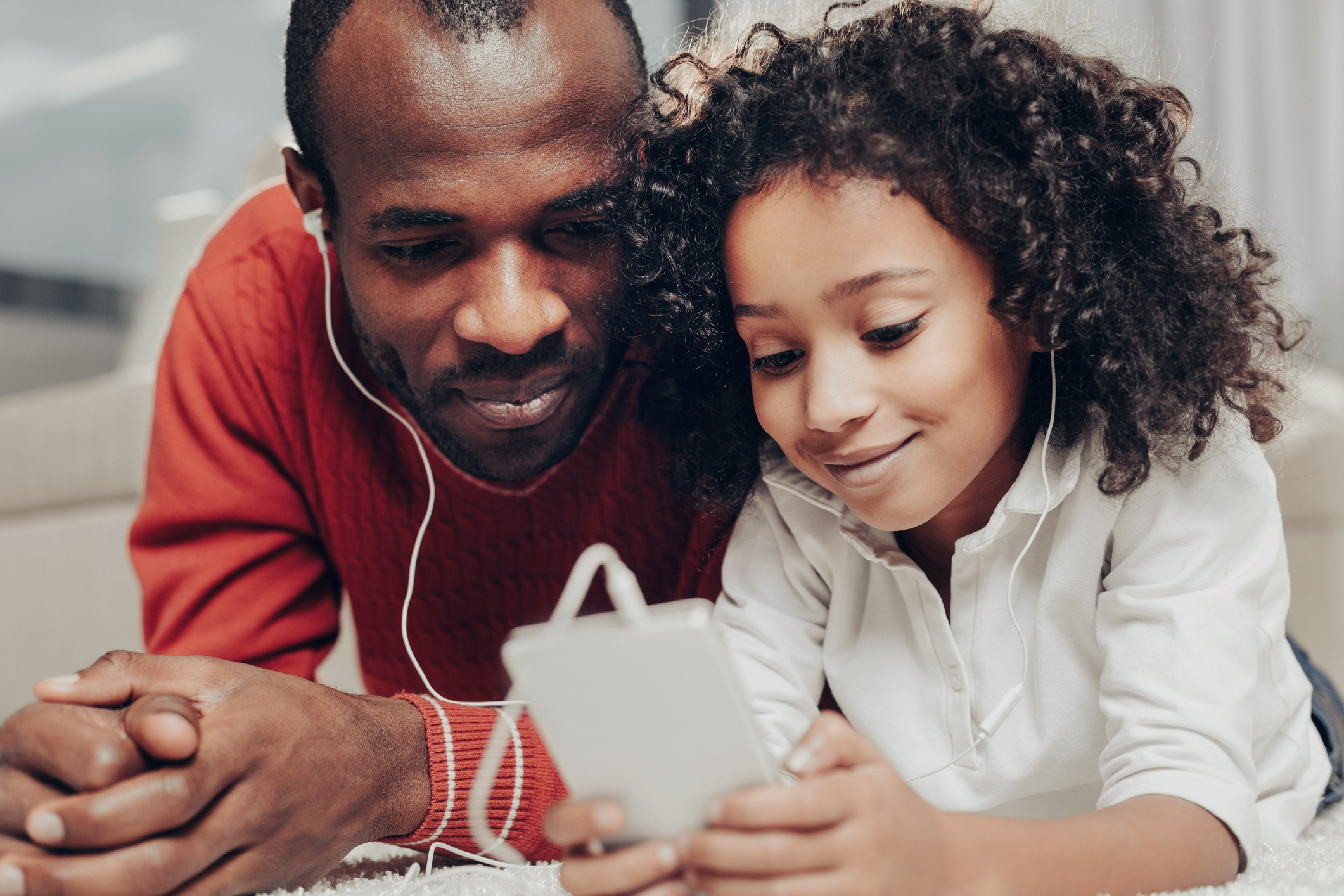 Satisfied dad and child enjoying audiobooks with earphones