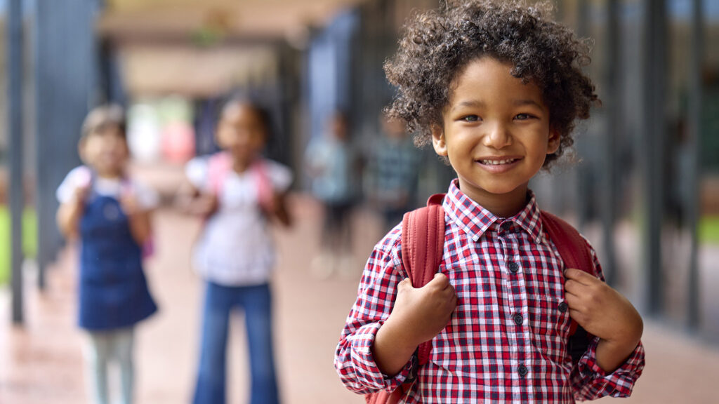 Portrait Of Smiling Male Elementary School Pupil Outdoors With Backpack At School